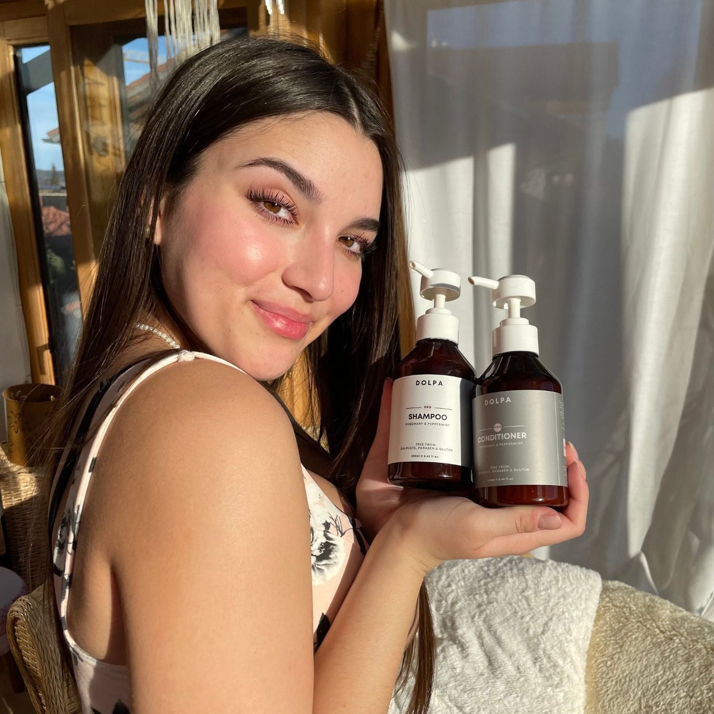An image of a woman with long, healthy hair, holding a bottle of hair growth shampoo and conditioner. The shampoo and conditioner bottles are prominently displayed with clear labels and images of nourishing ingredients such as biotin, keratin, and argan oil.
